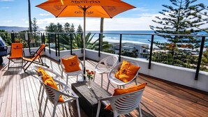Terraza con mobiliario exterior, una mesa y vista al océano.
