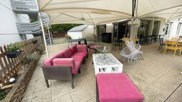 An outdoor patio area with a covered seating area, a dining table, and a grill.