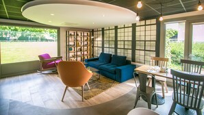 Una sala moderna con un sofá azul, una mesa de comedor de madera y un amplio ventanal con vistas a un área verde.