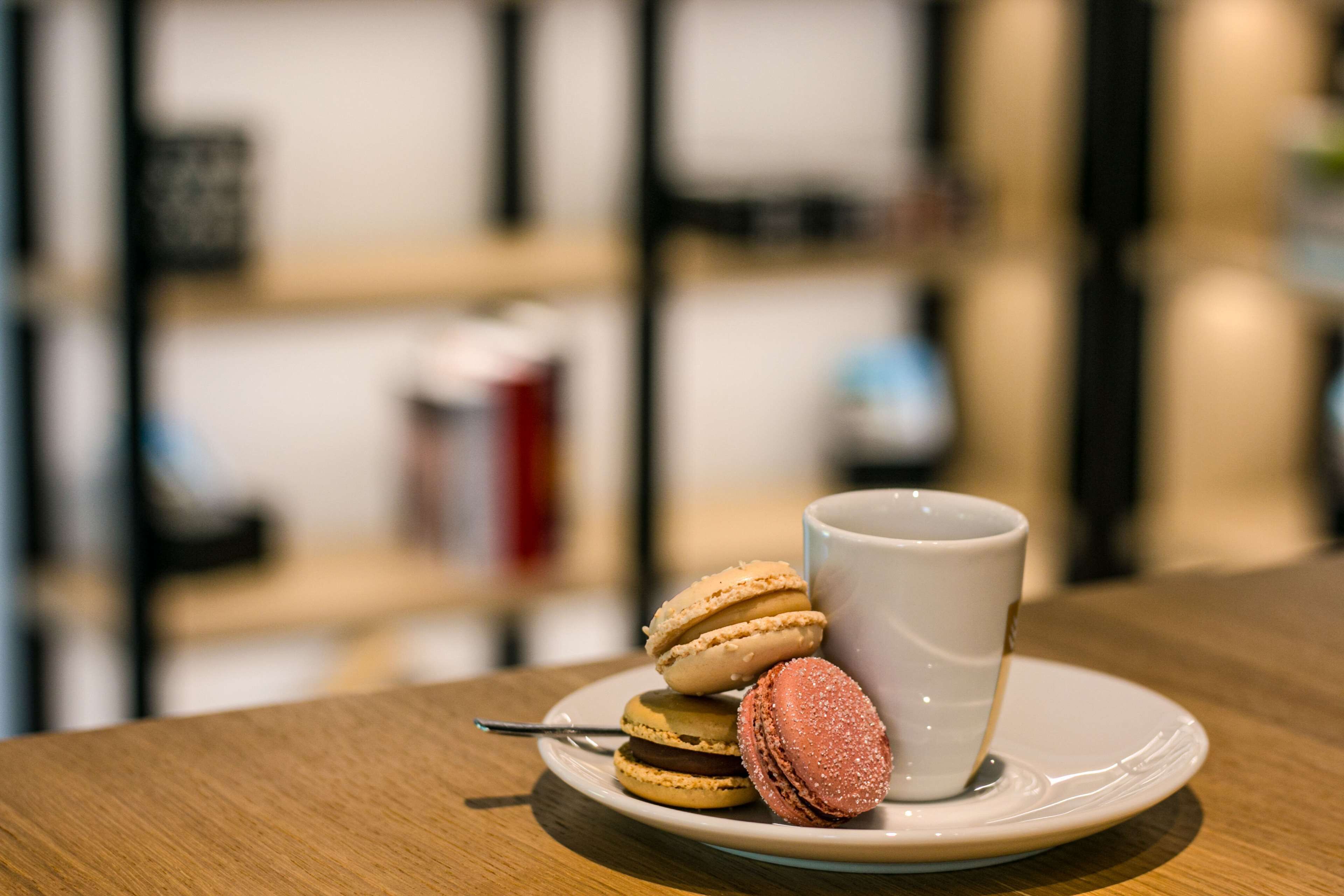 Un tavolo con una tazza bianca e un piatto di macarons.