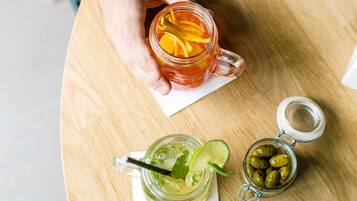 A hand holding a glass mug with a slice of orange and mint leaves.