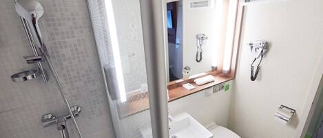Un baño pequeño con ducha, inodoro y lavamanos.