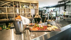 Zona de bar con una variedad de botellas, vasos, y una selección de comida y bebidas sobre la barra.