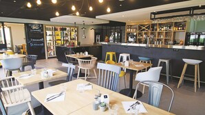 Un restaurante con varias mesas, sillas y una zona de bar.
