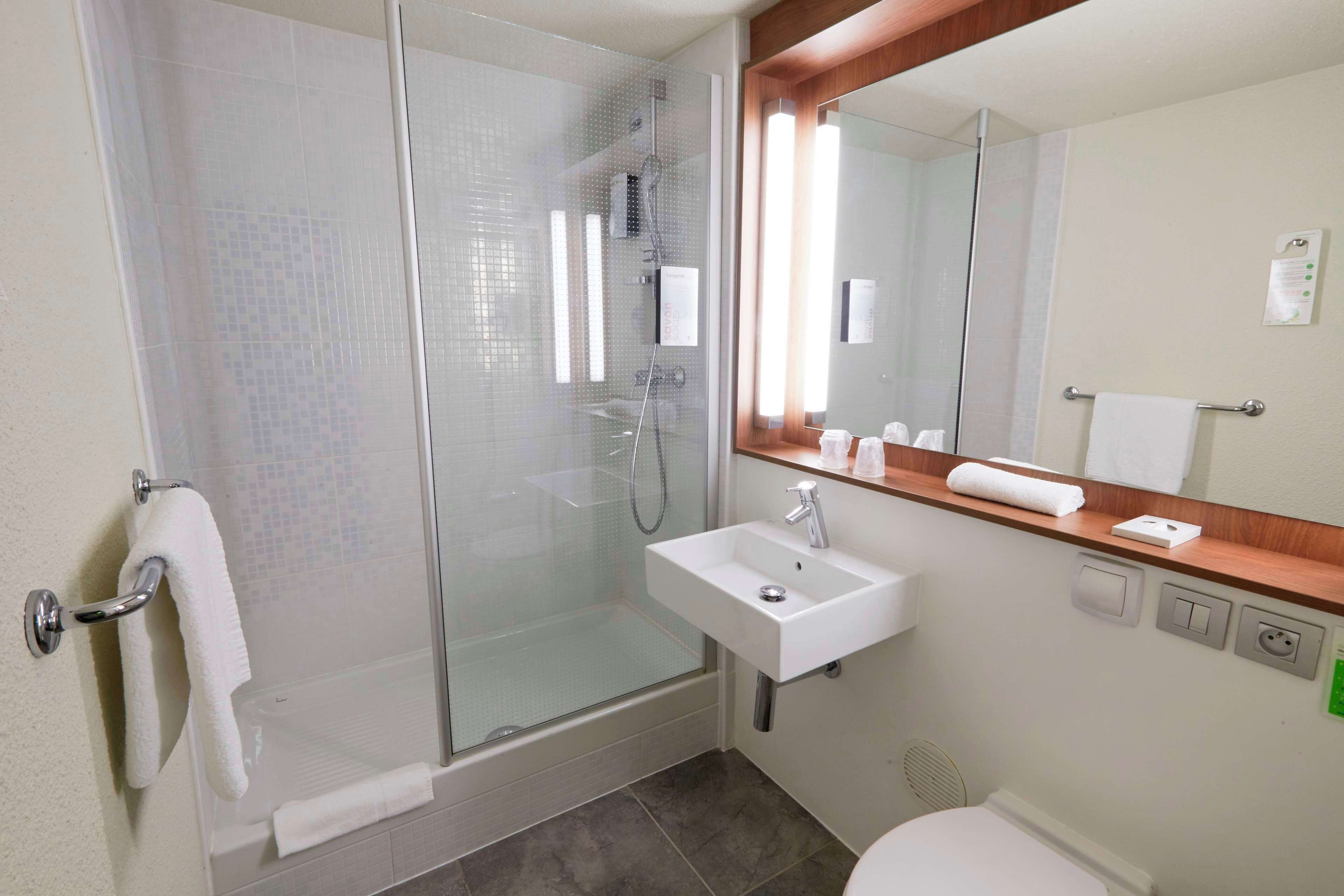 A bathroom with a glass-enclosed shower, a white sink, and a large mirror above the sink.