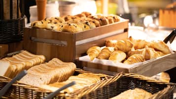 A variety of breads and pastries displayed in baskets and wooden trays.