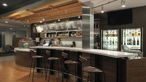 A modern bar area with a curved counter, bar stools, and a menu display.