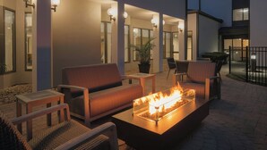 An outdoor seating area with a fire feature, wicker furniture, and a potted plant.