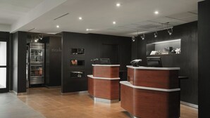 A modern reception area with a dark color scheme, two reception counters, a refrigerator, and a display shelf.