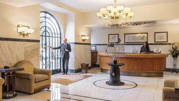 A lobby with a reception desk, a chandelier, and a large window.