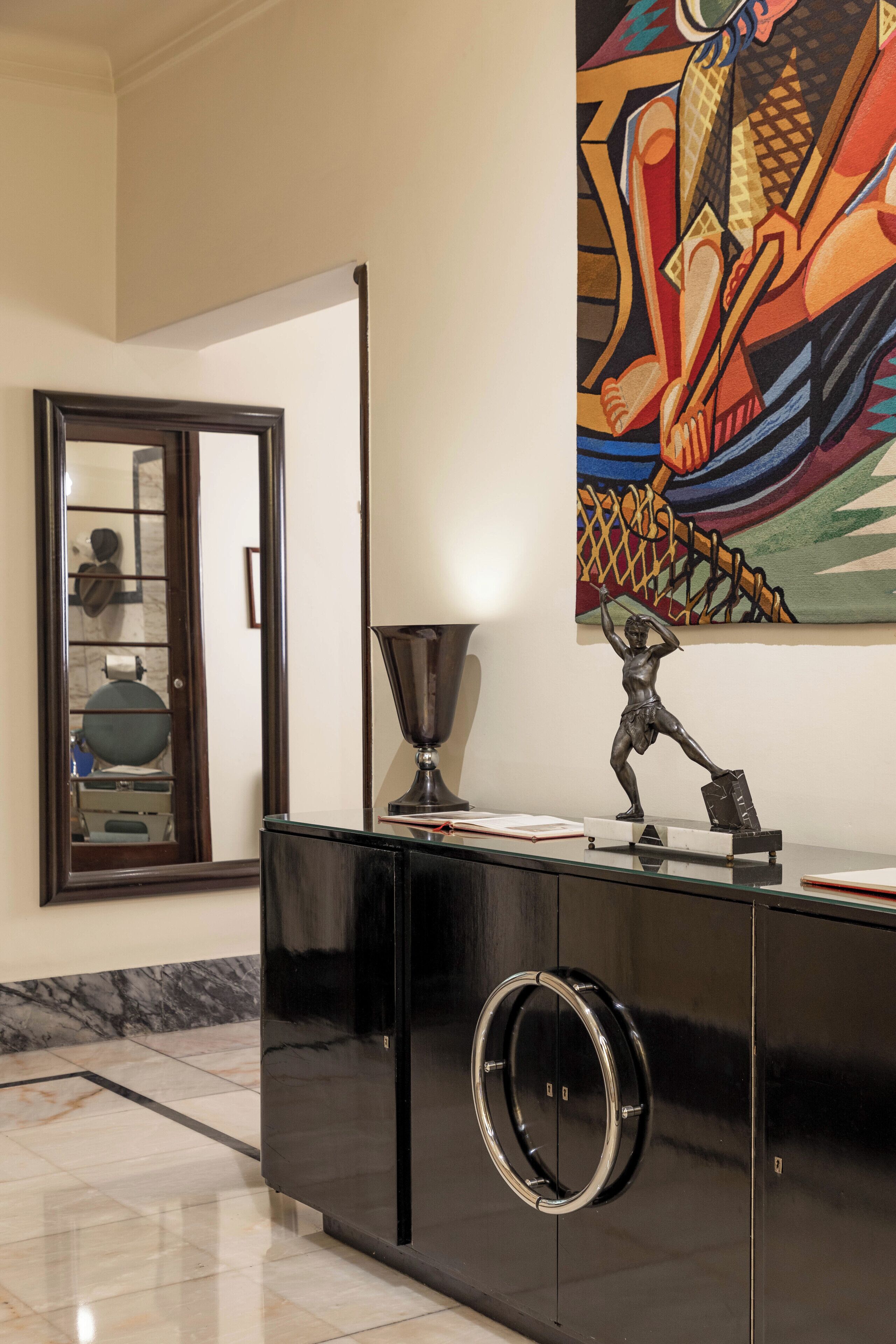 Un interior moderno con un mueble negro, una puerta de cristal y un cuadro abstracto colorido en la pared.