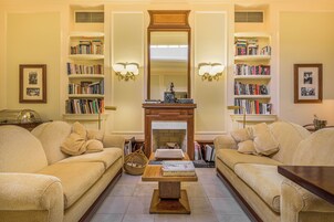 A living room with two beige sofas, a wooden coffee table, and bookshelves on either side.