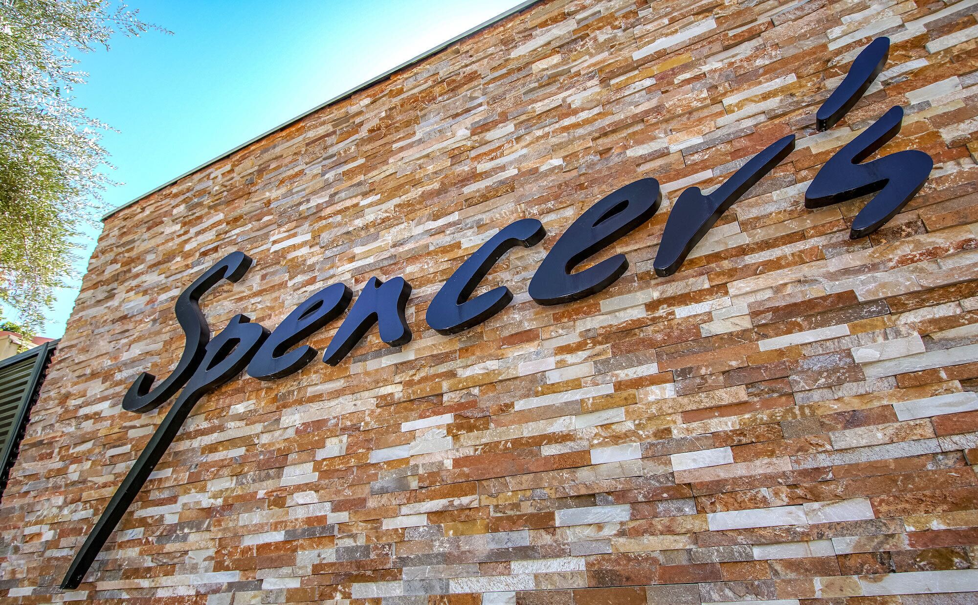 Un mur de briques sur lequel est inscrit en grandes lettres sombres le nom « Spencer's ».