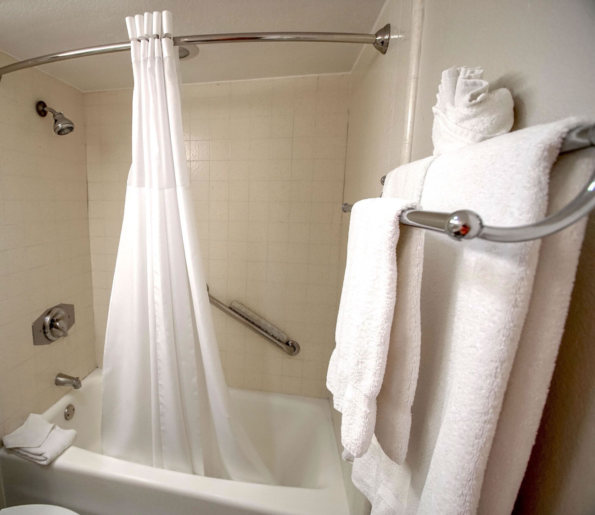 A bathroom with a bathtub, a shower curtain, a towel rack, and a toilet.