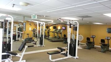 A gym with various exercise equipment, a treadmill, and an exit sign.
