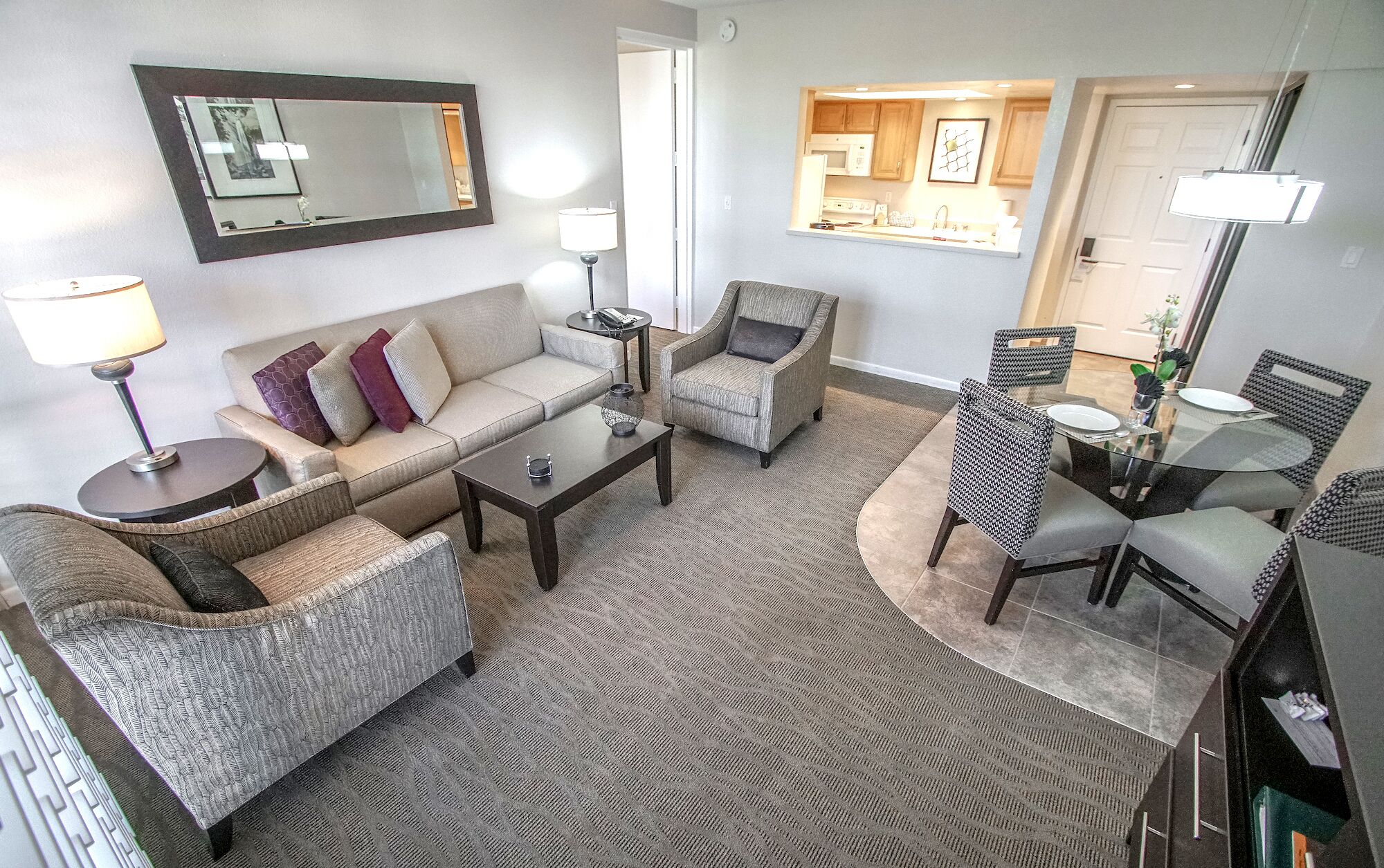 A living room with a sofa, armchairs, a coffee table, and a dining area with chairs and a table.