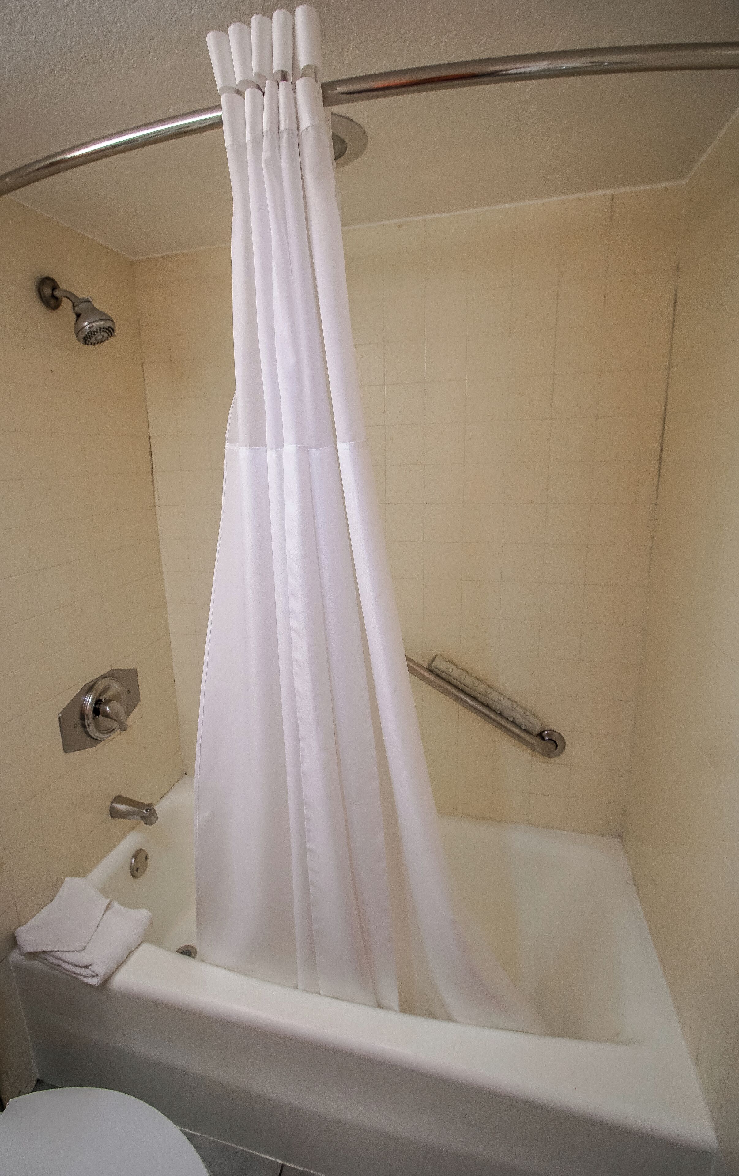 A bathroom with a bathtub, a showerhead, and a curtain.