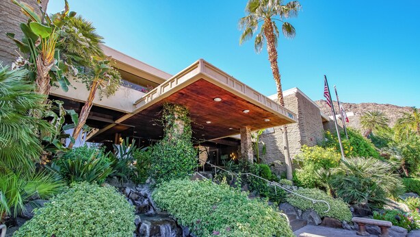 A hotel with a waterfall, palm trees, and a covered outdoor area. - Palm Springs Tennis Club (Palm Springs)