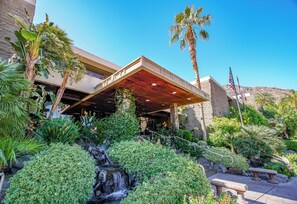 A hotel with a waterfall, palm trees, and a covered outdoor area. - Palm Springs Tennis Club (Palm Springs)