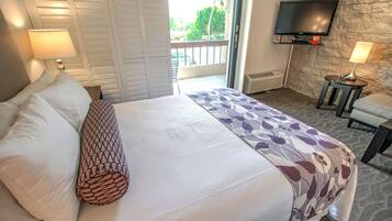 A hotel room with a bed, two bedside lamps, a television on the wall, and a small table with a lamp.