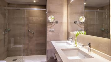 Une salle de bain moderne avec une douche à parois de verre, un grand miroir et deux lavabos.