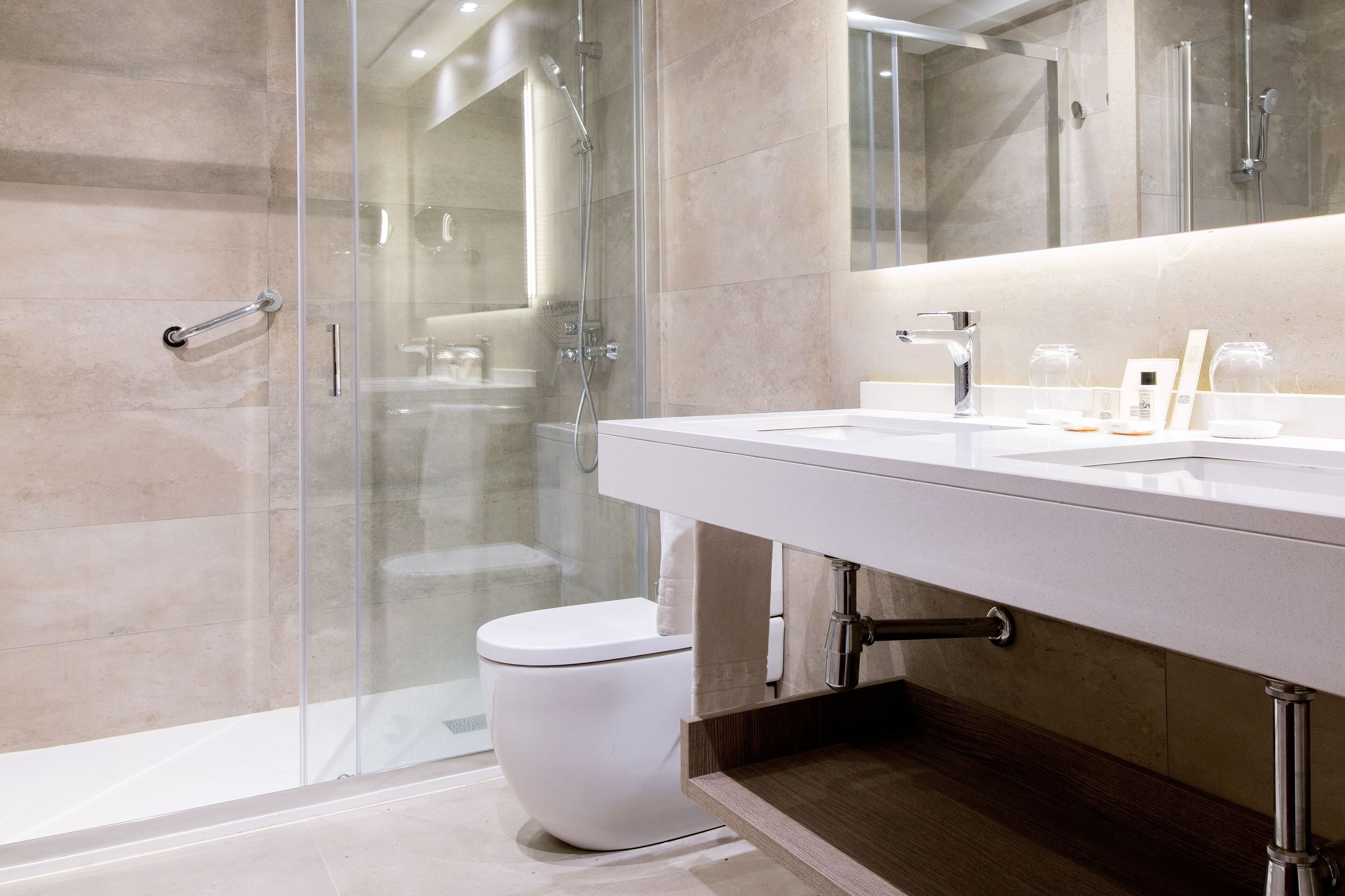 Un baño moderno con cabina de ducha de vidrio, inodoro blanco y tocador con espejo.