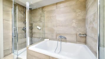 Un bagno moderno con doccia vetrata, una vasca da bagno ampia e rivestimenti in piastrelle color beige.