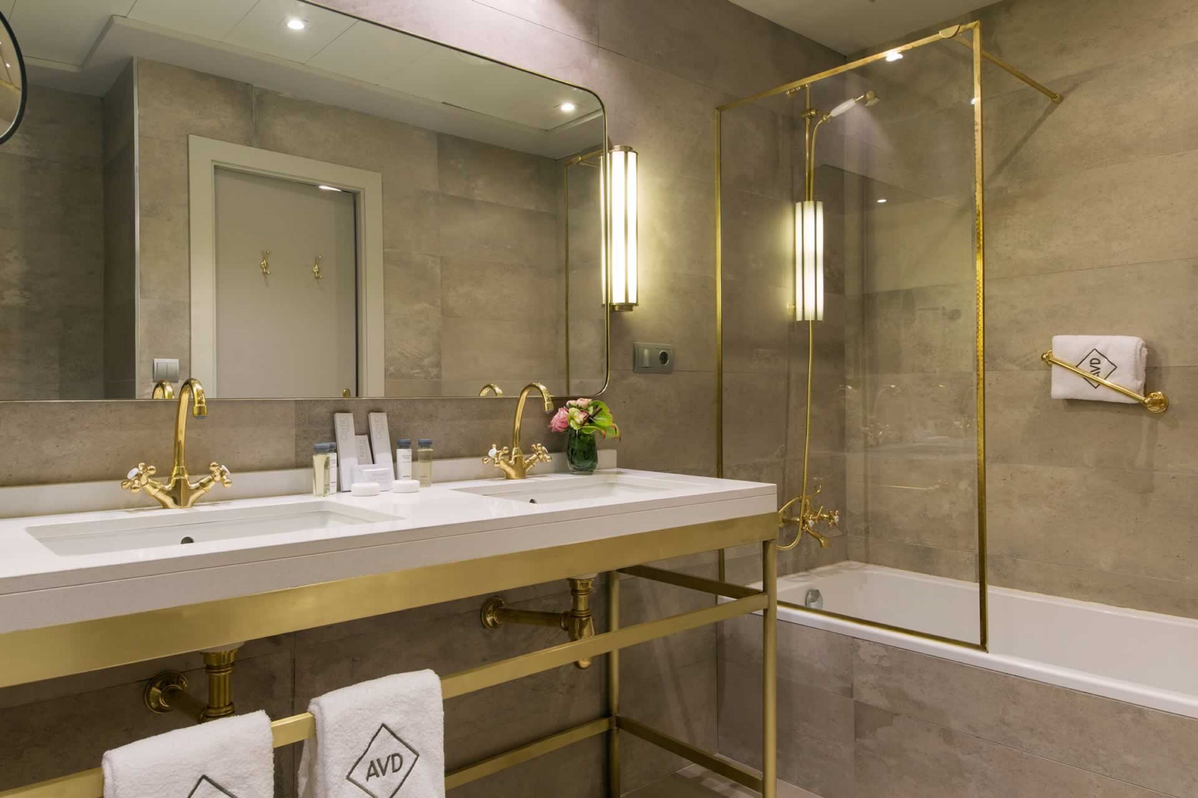 A modern bathroom with two sinks, a large mirror, and a glass-enclosed shower.