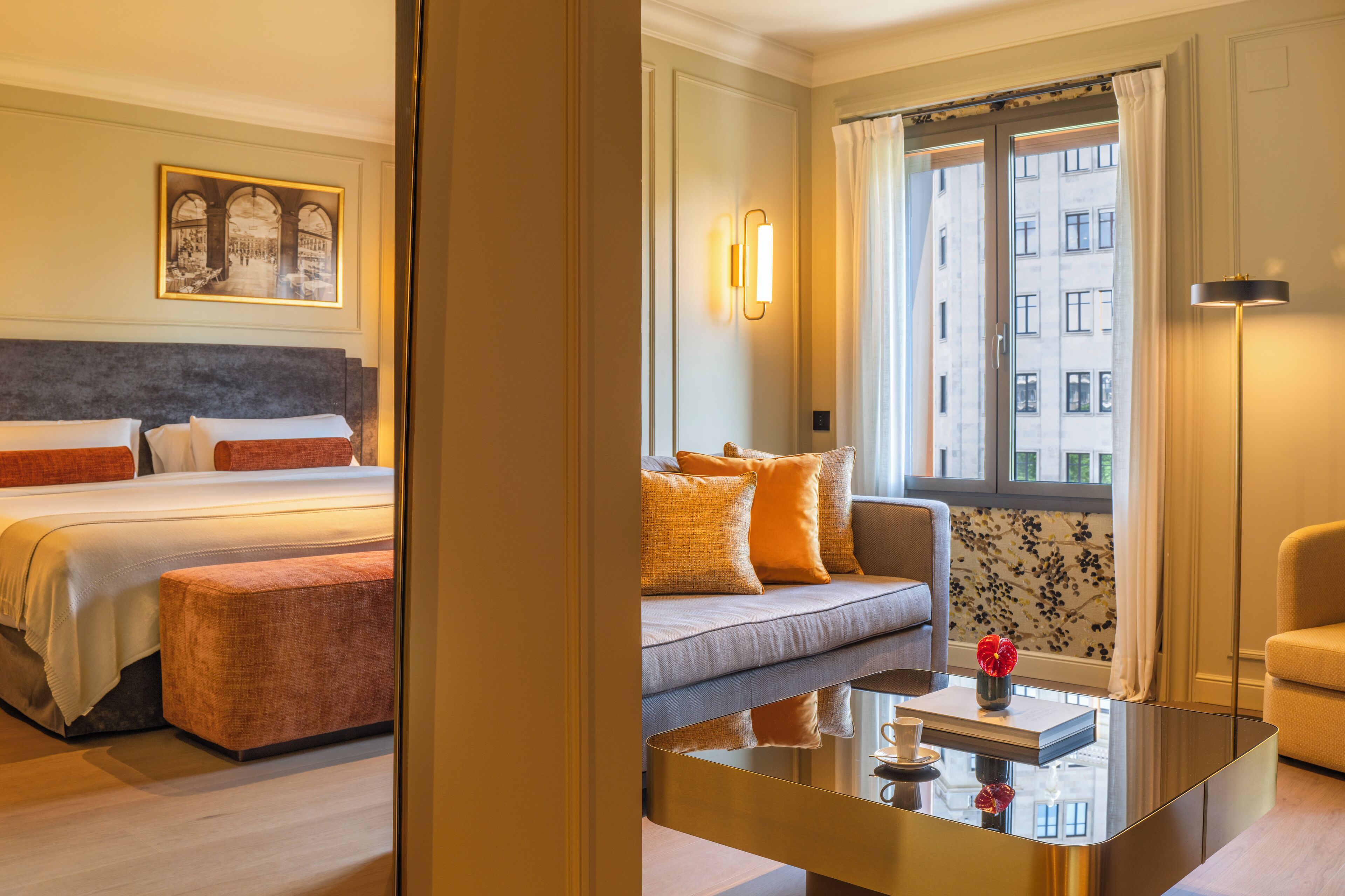 Una habitación de hotel con cama, sofá, mesa de centro y ventana con cortinas.