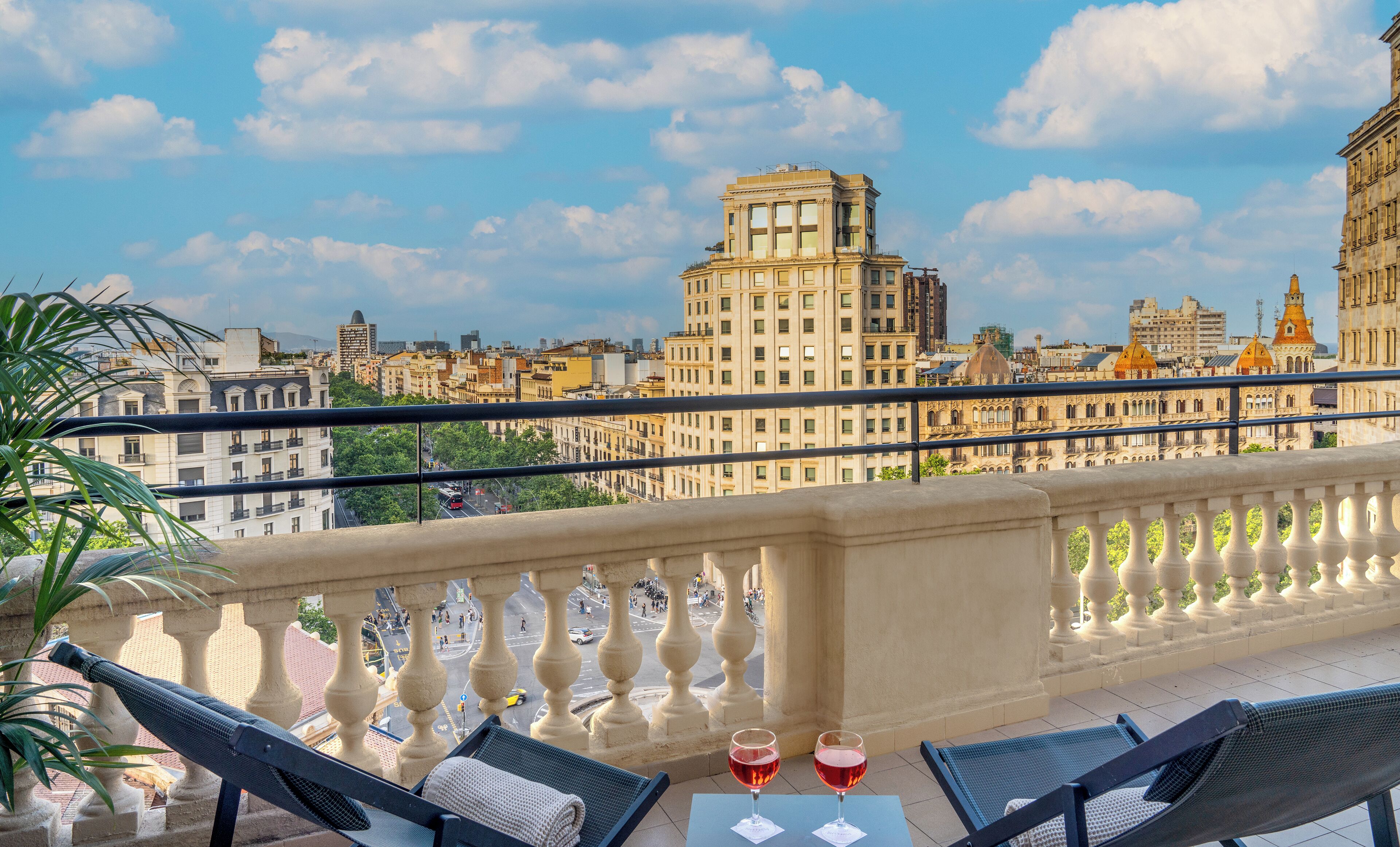 Un balcón con mesa y sillas, con vista a un paisaje urbano y edificios históricos.