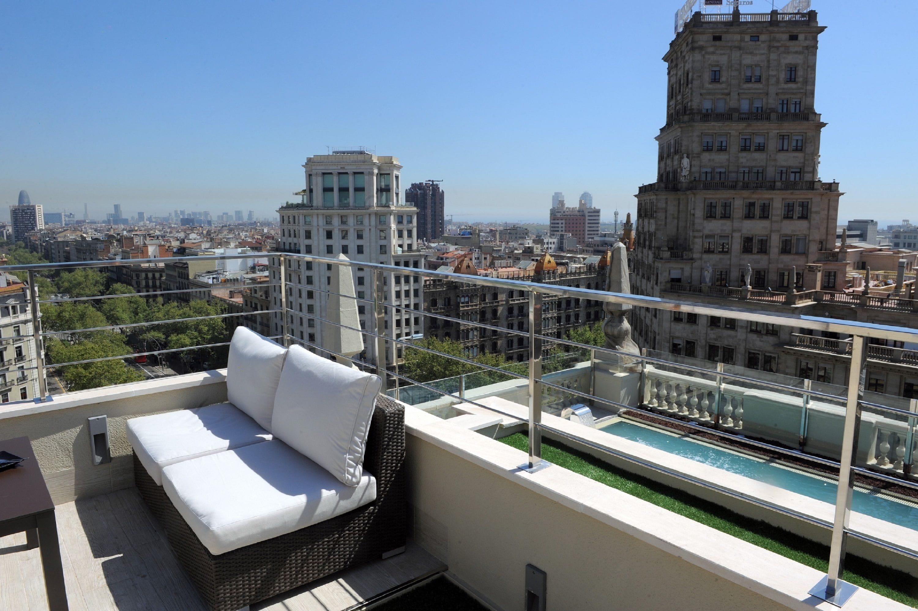 Terraza en la azotea con un sofá blanco, piscina y vistas panorámicas de la ciudad.