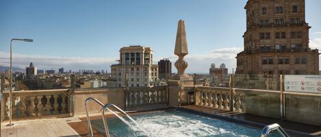 A rooftop pool with a clear view of the cityscape, including a prominent building with a sign.