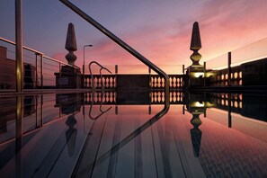 Et spejlende dæk med gelændere og et gelænder, der afspejler solnedgangen og en lygtepæl.