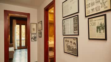 A hallway with framed historical documents and photographs on the walls, leading to a room with a wooden door and a visible bathroom.