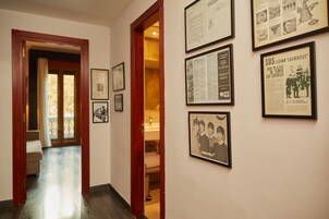 A hallway with framed historical documents and photographs on the walls, leading to a room with a wooden door and a visible bathroom.