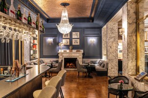 A bar area with a fireplace, seating, and a chandelier.