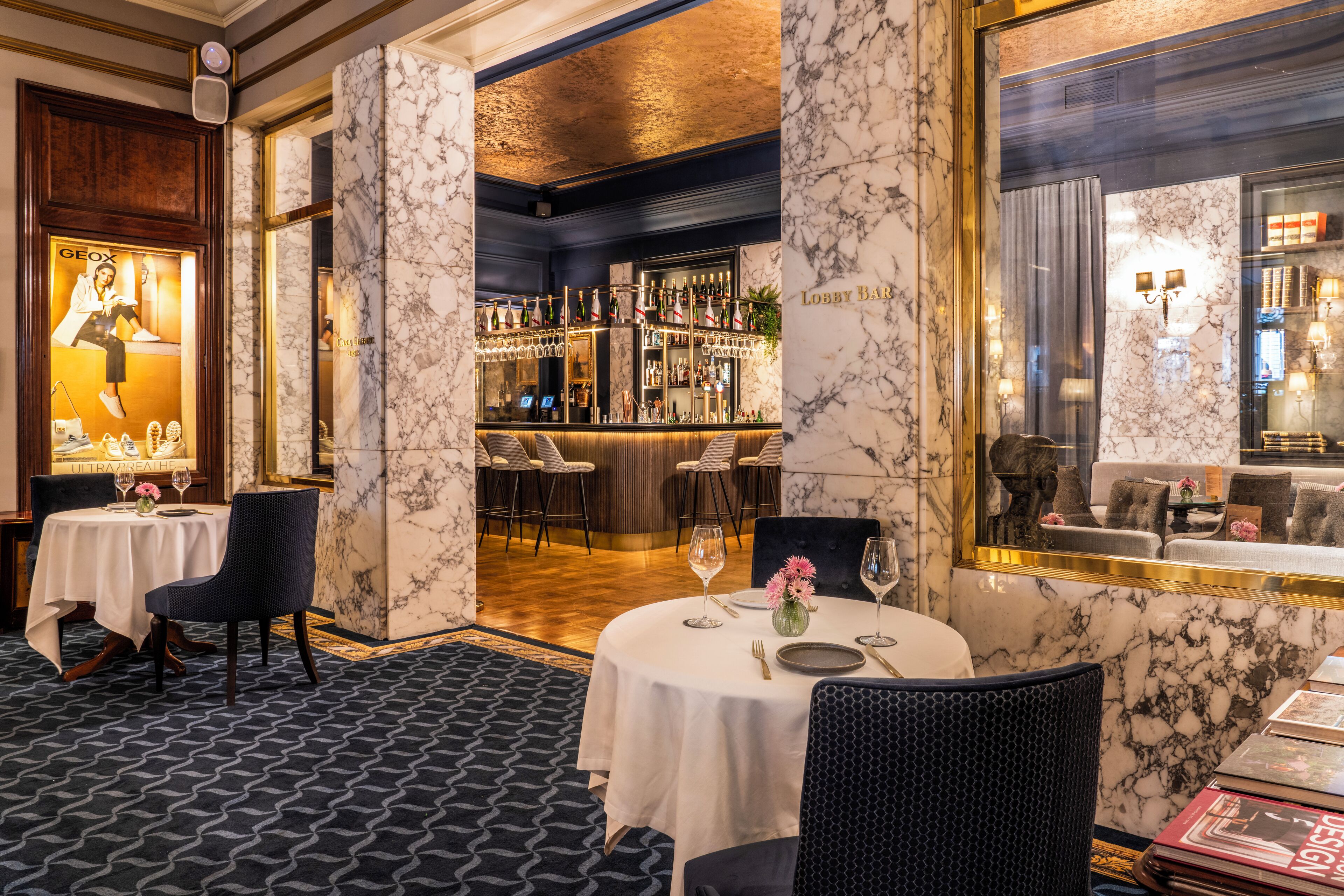Un hall d’hôtel aux murs de marbre, avec un bar et des espaces aménagés pour s’asseoir.