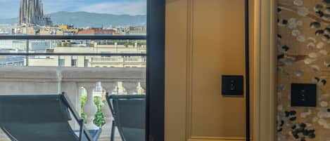 Una habitación con vistas a un paisaje urbano, una lámpara moderna, un papel tapiz estampado y una silla.