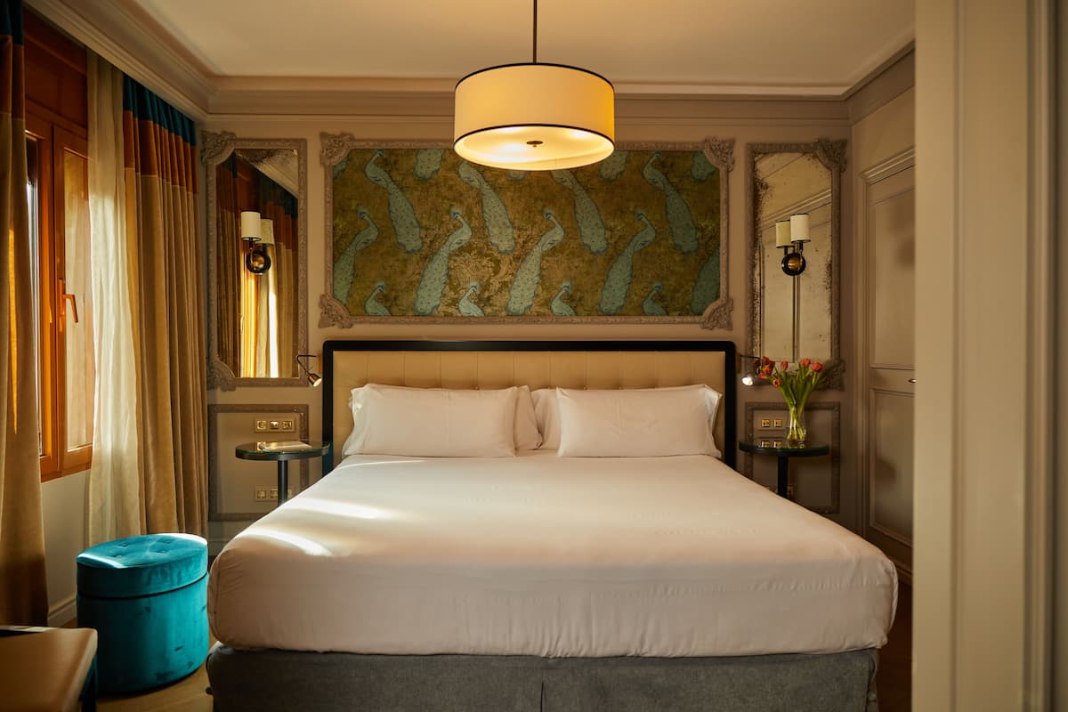 Une chambre d’hôtel avec un grand lit, une table de chevet, une lampe et un mur décoratif.