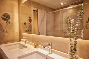 Uma casa de banho moderna com duas lavatórios, um espelho grande e um chuveiro.