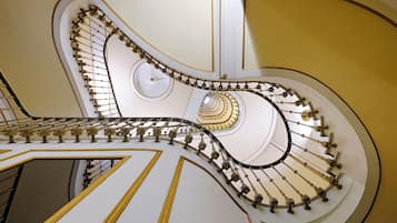 Uma imponente escadaria em espiral com detalhes em ouro requintados e paredes brancas.