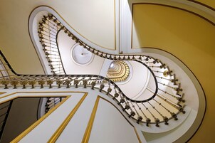 Uma imponente escadaria em espiral com detalhes em ouro requintados e paredes brancas.