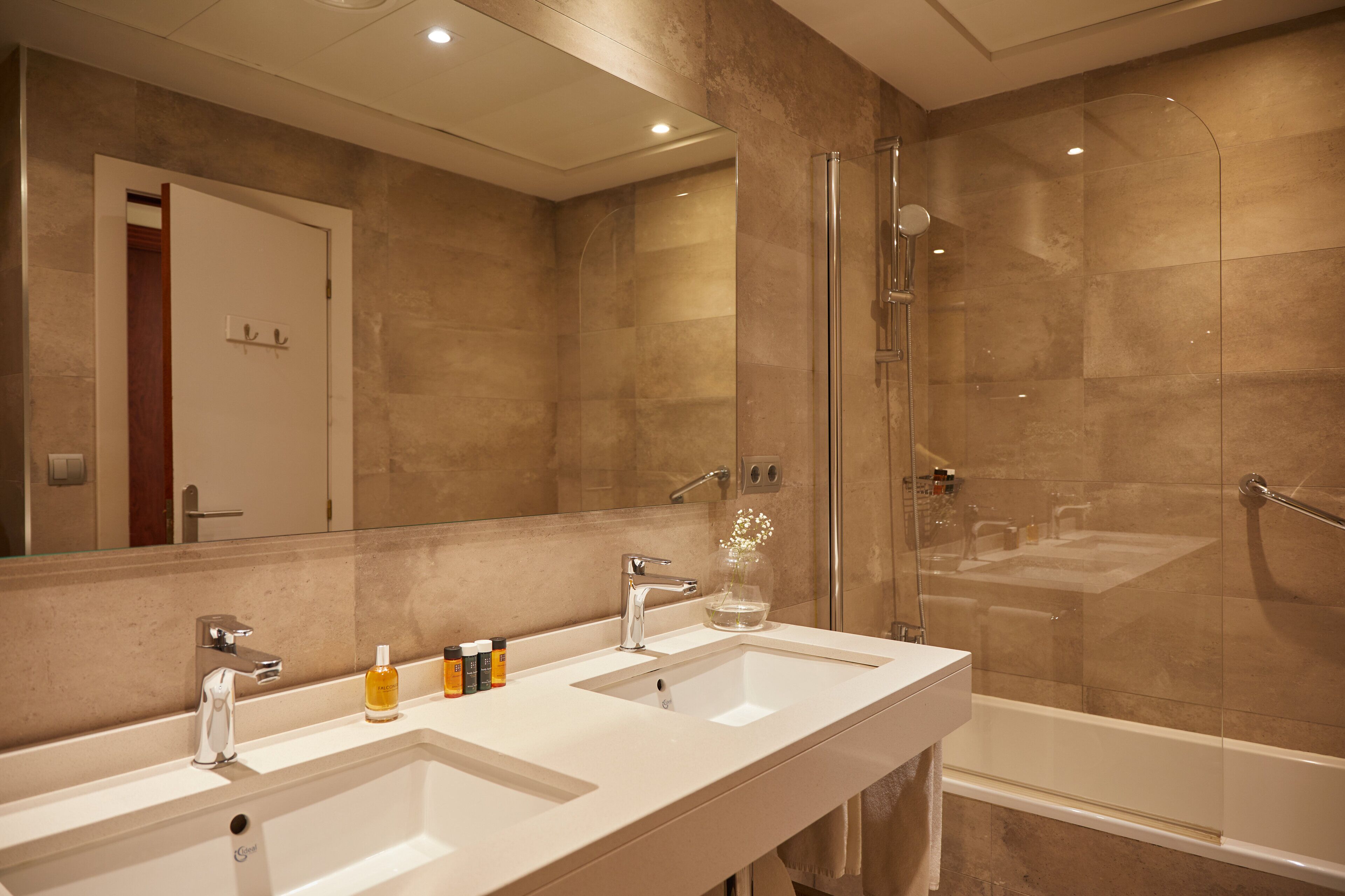 Een moderne badkamer met twee wasbakken, een douchecabine van glas en een grote spiegel.