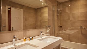 A modern bathroom with two sinks, a glass shower enclosure, and a large mirror.