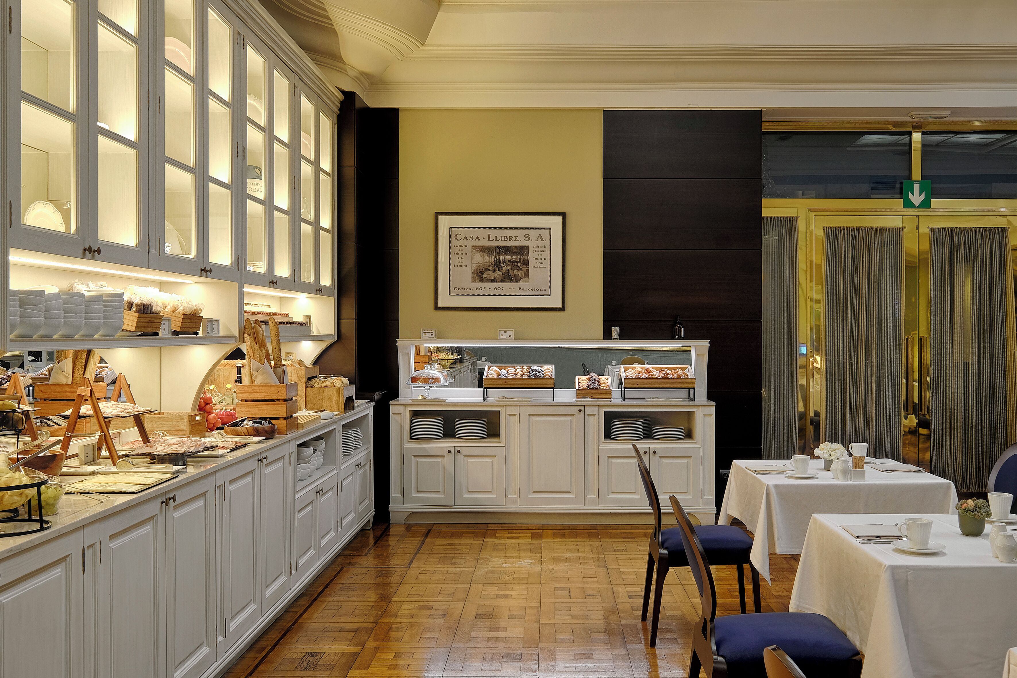Espaço de buffet de café da manhã com armários brancos e um quadro na parede.