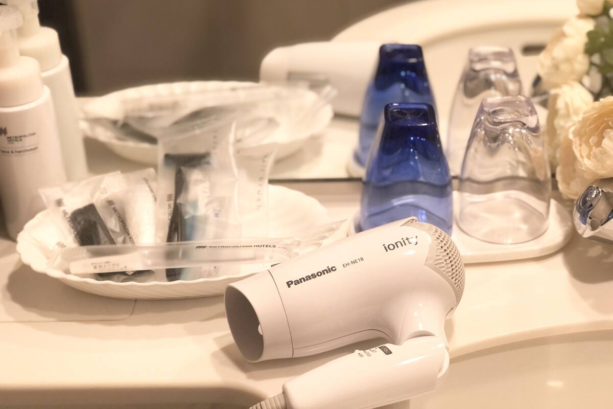 A bathroom vanity with a Panasonic hairdryer, a blue water bottle, and a white soap dispenser.