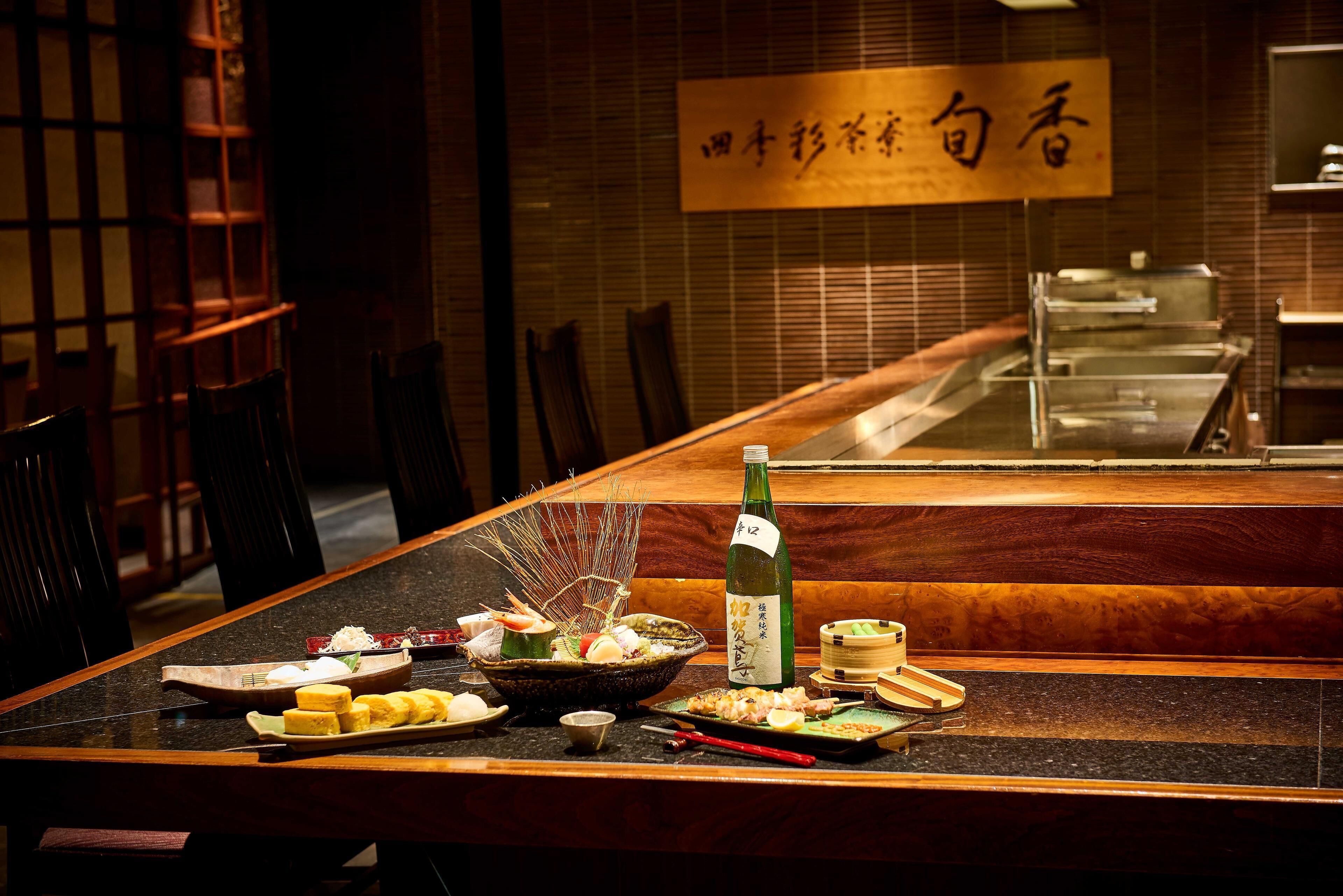 A dining table with various dishes, a bottle, and chopsticks.