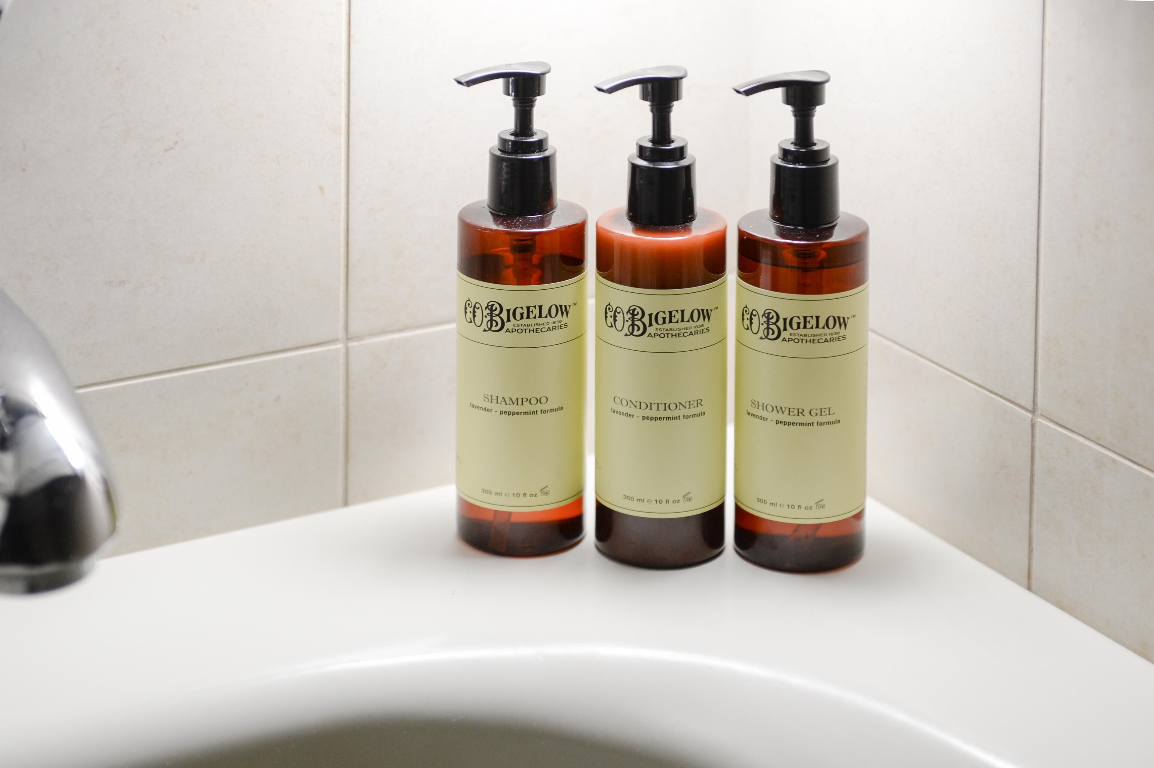 Tre bottiglie di shampoo, balsamo e gel doccia Bigelow su un lavabo da bagno.