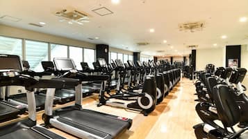 Et fitnesscenter med flere løbebånd og motionscykler stillet op i rækker.