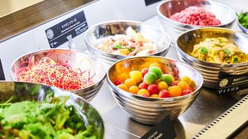 A buffet with various dishes including colorful tomatoes, shredded vegetables, and a salad.